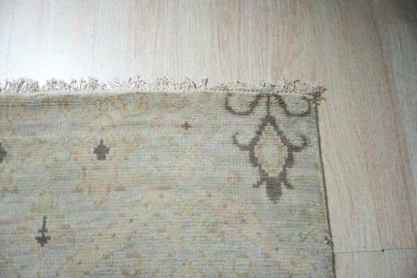 Lush traditional gray hand knotted wool rug 2 Textured cream rug featuring subtle beige and charcoal geometric patterns shown on light wood planks.
