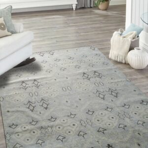 Light blue rug with dark gray scattered geometric patterns on light gray wood flooring.