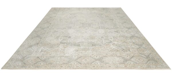 A large rectangular rug featuring complex faded geometric patterns in light gray, beige, and cream tones.