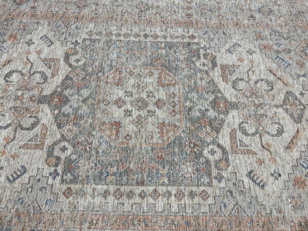 Distressed traditional rug in gray and cream colors with rust and blue accents and a faded medallion design.