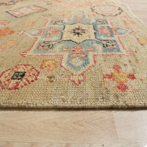 Textured beige rug with blue, orange, pink, and yellow geometric designs, resting on light wood floorboards.