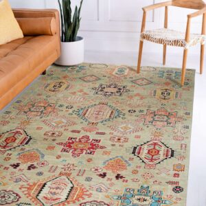 Geometric sage rug with tribal designs lies between a cognac leather sofa and a wooden chair.