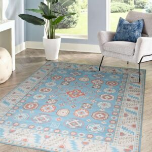 A blue and peach geometric patterned area rug lies on herringbone flooring next to a gray armchair.