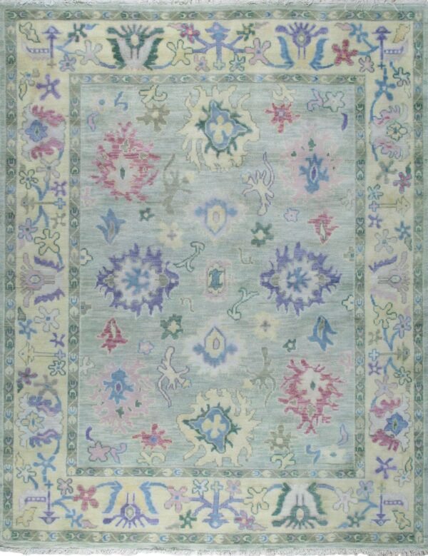 The rug has a light aqua field and ivory border with stylized floral patterns in pink, purple, and green.