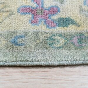 Cream rug with pastel pink, blue, and sage floral patterns and high pile texture on light wood flooring.