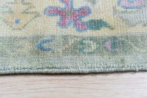 Cream rug with pastel pink, blue, and sage floral patterns and high pile texture on light wood flooring.