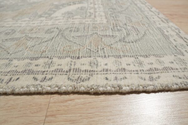High-pile ivory rug with a muted sage and grey traditional pattern rests on light wood flooring.
