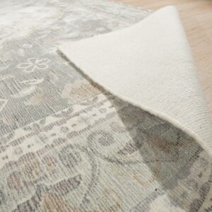 Gray patterned rug rolled back to expose the light woven backing on blonde wood flooring.