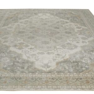 Muted traditional rug in soft gray, off-white, and beige colors featuring an ornate distressed central medallion.
