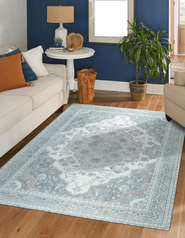 Pale blue and gray traditional rug centered on hardwood floors in a room with a cream sofa and navy wall.
