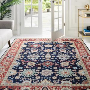 Traditional blue rug with multicolored botanical patterns covers a white floor near open patio doors.