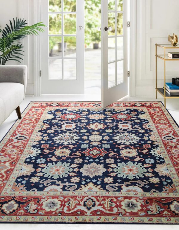 Traditional blue rug with multicolored botanical patterns covers a white floor near open patio doors.