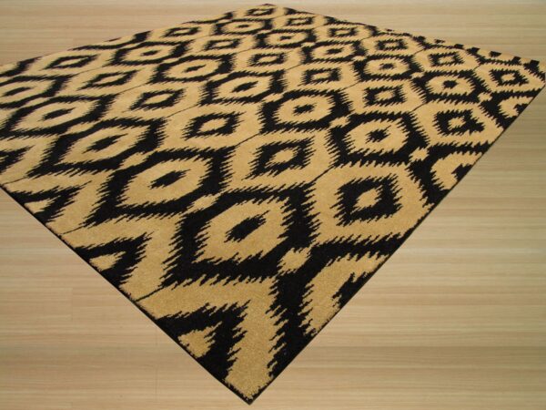 A black and tan rug featuring an abstract ikat diamond pattern rests diagonally on light wood flooring.