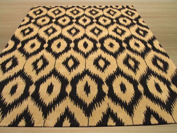 Black and tan medium-pile rug with large ikat diamond pattern resting on light wood floor.