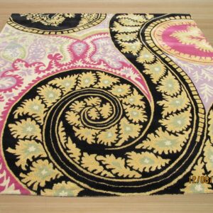 Plush rug with a massive swirling paisley pattern in black, gold, bright pink, and lilac on a light wood floor.