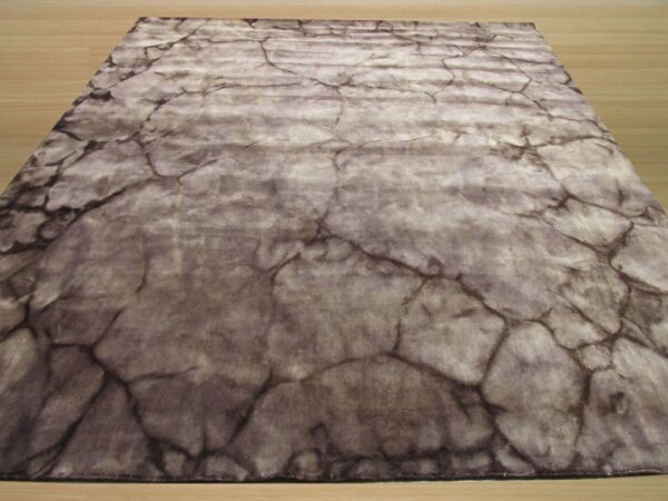 Gray and taupe low-pile rug with a distressed cracked stone pattern on light wood floor.