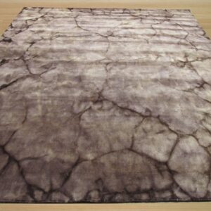 A gray and taupe rug featuring a distressed cracked stone pattern is displayed on light wood flooring.