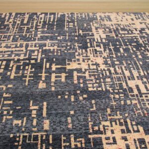 A dark gray rug with an abstract geometric beige pattern rests on light wood floor.