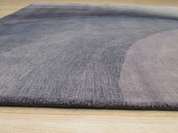 Medium-pile rug with blue and gray abstract gradient pattern shown on light wood flooring.