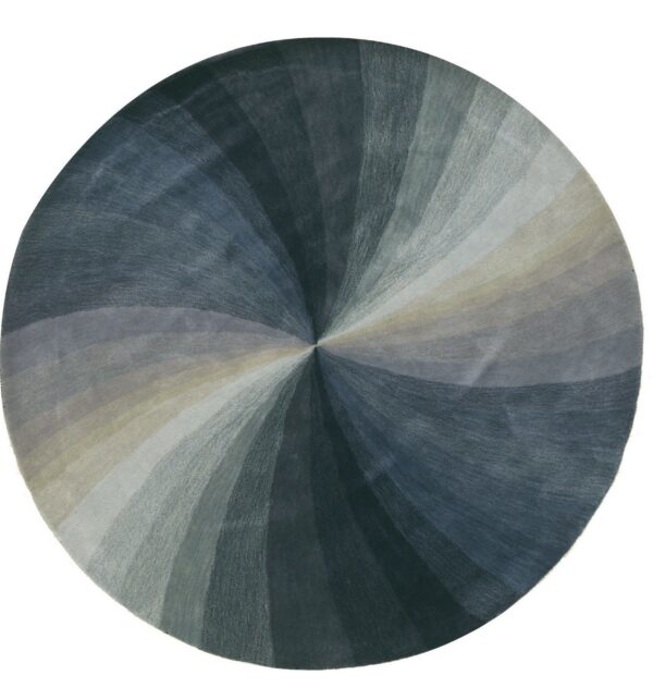 Round rug displays a radial pattern in varying shades of slate blue, dark gray, and light tan wedges.