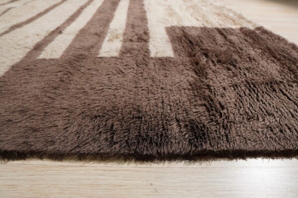 A textured high-pile shag rug in brown and beige stripes rests on light wood planks.