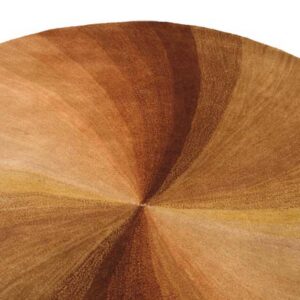 Close-up of a round rug featuring radiating bands of deep brown, amber, and gold hues.