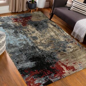 Abstract rug in gray, black, beige, red, and light blue rests on a wood floor beside a dark sofa.