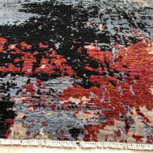 Abstract rug featuring red, black, and blue-gray distressed patches on a light wood floor.