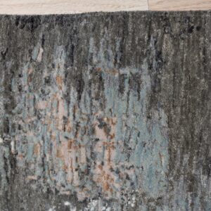 Textured gray rug with an abstract design in blue and beige shown on light wood flooring.