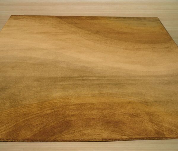 Gold plush rug displaying a subtle swirling pattern rests on light blonde wood planks.