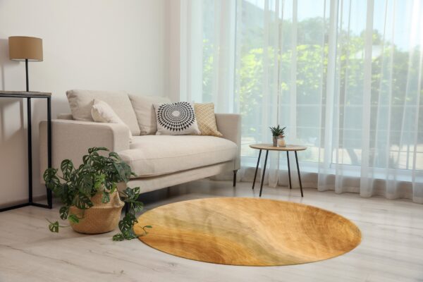 Round rug with wavy yellow and gold stripes complementing a cream sofa on light wood floors.