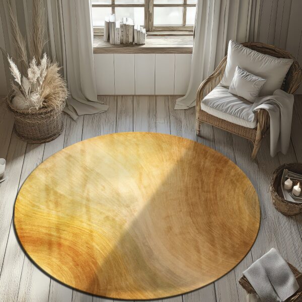 Round gold and brown gradient rug on whitewashed wood floors by a window and rattan chair.