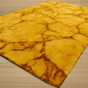 A golden yellow plush rug with a brown abstract cracked pattern rests on light wood plank flooring.