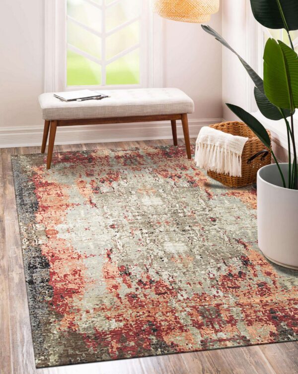 Gray and reddish-orange abstract rug placed under a small upholstered bench on wood plank flooring.