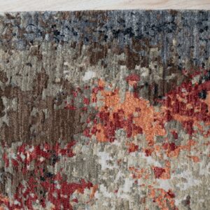 Textured area rug showing abstract gray, brown, red, and orange patterns against light plank flooring.
