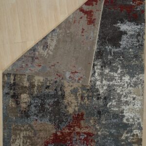 Abstract low-pile rug featuring dark gray, beige, white, and red distressed patterns on light wood flooring.