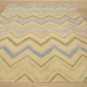 A pale yellow rug featuring a distressed zigzag pattern in blue and olive green on light wood flooring.