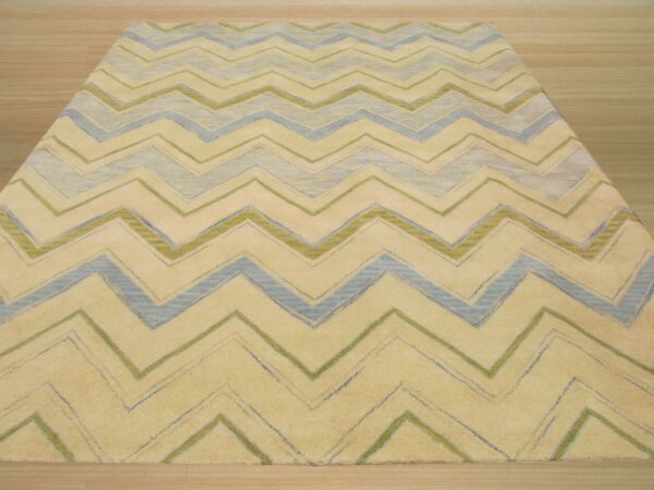 Yellow area rug with thick blue and green chevron patterns rests on hardwood floor.
