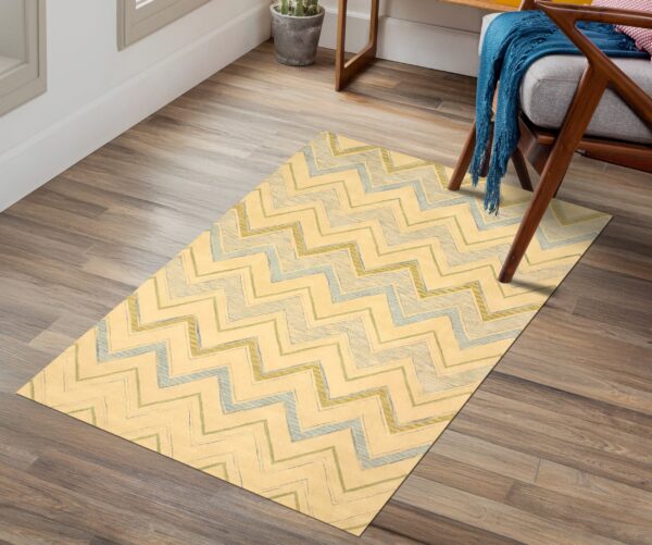 Rectangular yellow rug featuring textured blue and green zigzag lines, set under a wood chair on plank flooring.