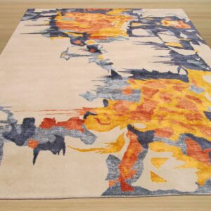 Beige rug featuring an abstract painterly pattern of golden yellow, rust, and slate grey on wood plank flooring.