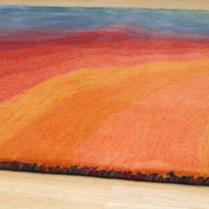 Textured rug with thick orange, red, and blue wavy color bands on light wood flooring.