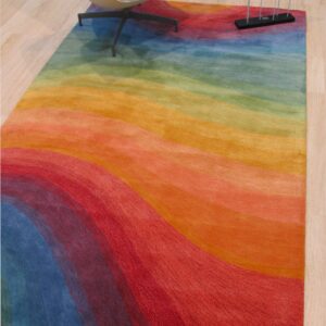 Multicolored rug with wavy bands of red, orange, yellow, green, and blue beneath a white accent chair.