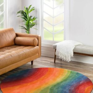 A brightly colored round rug featuring wavy rainbow bands sits on wood flooring near a tan leather sofa.