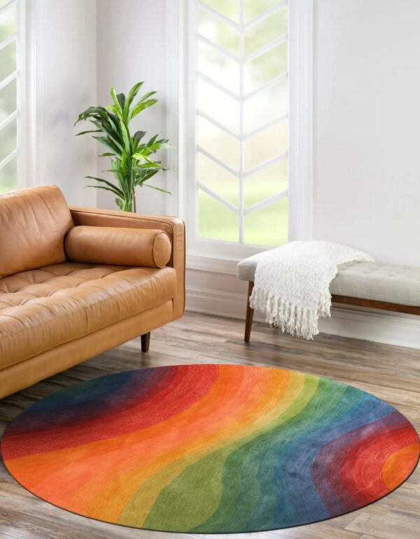 A brightly colored round rug featuring wavy rainbow bands sits on wood flooring near a tan leather sofa.