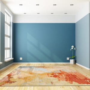 Abstract rug featuring orange, red, and blue tones on light wood flooring in a brightly lit room.