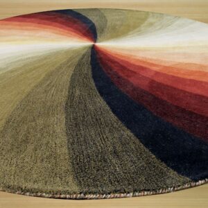 Highly textured round rug displaying bands of olive, red, and black radiating from the center on wood flooring.