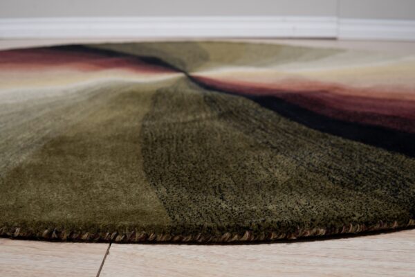 Plush round rug displays dark green, black, and red radiating stripes on light wood flooring.