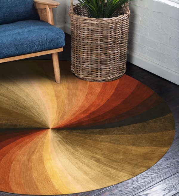 A round gold and orange radiating rug sits on dark wood floors near a blue chair and wicker basket.