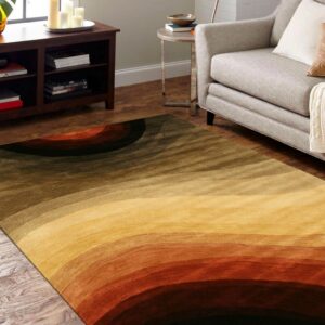 Brown and rust rug with concentric ombre stripes placed beneath a gray armchair on wood flooring.