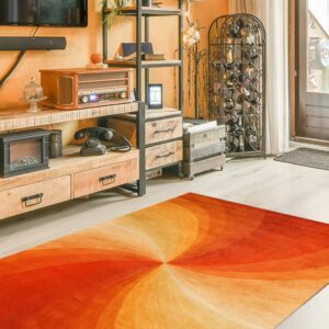 The orange and red vortex rug sits on light wood flooring in a rustic living room setting.